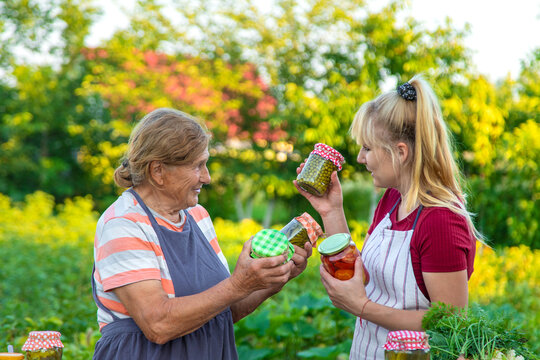 Women with jar preserved vegetables for the winter mother and daughter. Selective focus. - Powered by Adobe