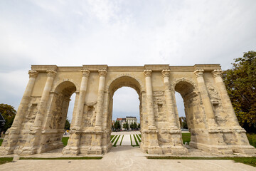 Obraz premium Reims, Marne, Grand-Est, France, August, 28th, 2025, Champagne Area, BAncient stone gateway with surroundings, Old stone triumphal arch overlooking manicured gardens and distant fountain