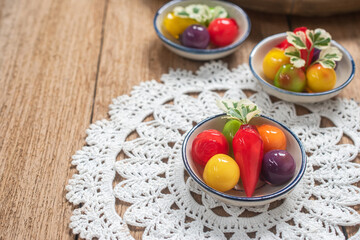 A beautifully arranged selection of colorful Thai Luk Chup—miniature fruit-shaped mung bean desserts—presented in small ceramic bowls with traditional blue-and-white patterns. 