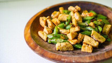 Stir-fried tofu with green beans in a rustic wooden bowl