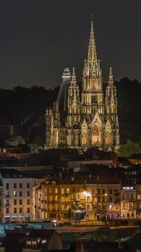 Aerial view of Notre Dame de Laeken church spires night timelapse in Brussels, Belgium. Neo-gothic architecture surrounded by historic facades, lush park areas and illuminated urban scenery