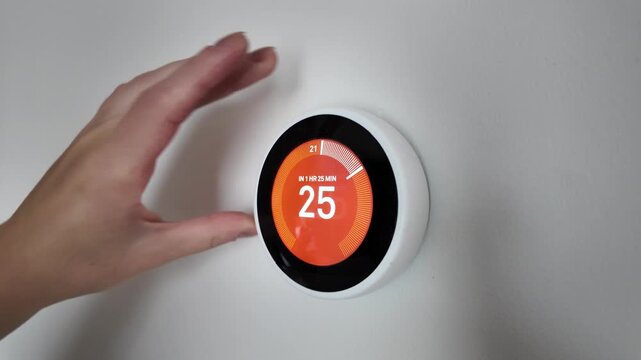 Adult hand rotates circular digital interface for temperature adjustment - Powered by Adobe