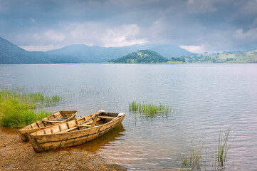 Obraz premium Small wooden boats anchored off Umiam Lake under heavy monsoon clouds. Shillong, Meghalaya, India.