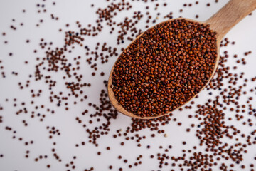 Red Quinoa Seeds on a Wooden Spoon with Scattered Grains