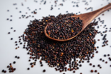 Black Quinoa Seeds with Wooden Spoon on White Background