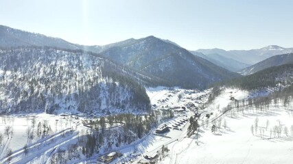 Snowy mountain ridges rise above conifer forests aerial vista highlights peaceful cold wilderness. Soft frost glistens across treetops - Powered by Adobe