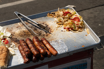 Authentic Street Food: Grilled Hot Dogs and Onions on a Vendor Cart