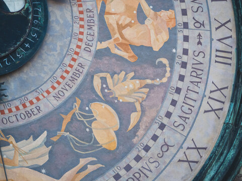 Detailed view of an ancient astrological clock dial, depicting intricate zodiac constellation symbols and precise calendar months
