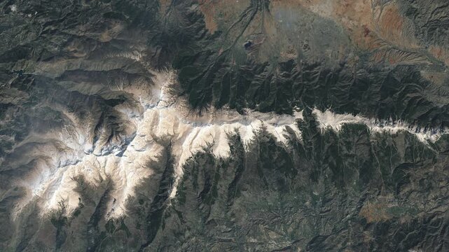 Aerial shot of mountain ridge covered with snow. Camera is moving backward. Animation based on image by NASA
