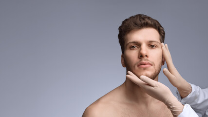 Doctor assessing male face before aesthetic injection procedure. Concept of symmetry check, treatment planning, facial evaluation, and modern cosmetic preparation.