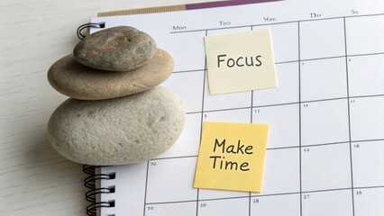 Stones balancing on a calendar with focus and make time notes