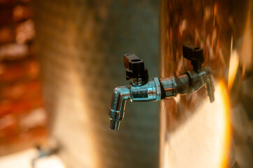 Artisanal winery equipment. Gleaming stainless steel fermentation tanks within a dimly lit industrial space, accented with colorful light reflections.