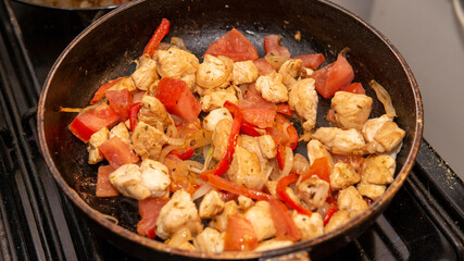 chicken, onion and bell peppers  sauteed in a frying pan