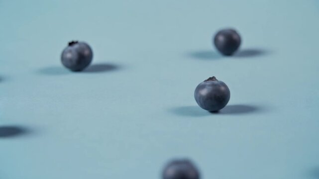A bunch of blueberries rolling down a flat color surface, bouncing and changing direction