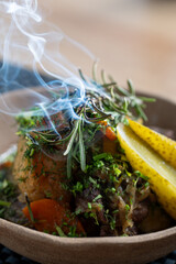 Close-up of a steaming dish garnished with fresh rosemary and herbs creating an enticing aroma.