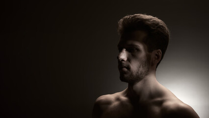 Fototapeta premium Low-key side portrait of man with nasal bandage illuminated by narrow dramatic beam. Concept of cosmetic surgery recovery, emotional storytelling, and visual narratives for healthcare communication.