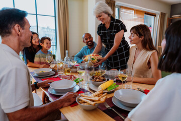 Family and friends reunion at home. Multigenerational family gathering enjoying dinner party meal together