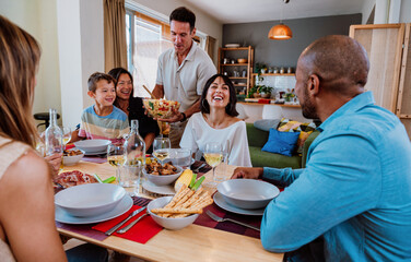 Family and friends reunion at home. Diverse family gathering enjoying dinner at home