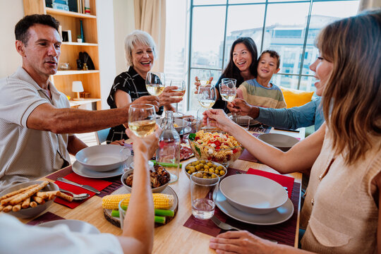 Family and friends reunion at home. Diverse family and friends celebrating together making a toast - Powered by Adobe