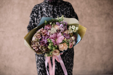 Very nice young woman holding big and beautiful bouquet of fresh flowers in colors