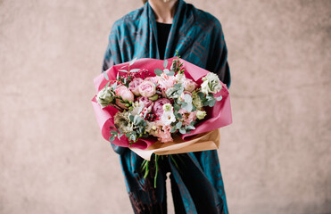 Very nice young woman holding big and beautiful bouquet of fresh roses, eustoma, eucalyptus flowers in pink and white colors
