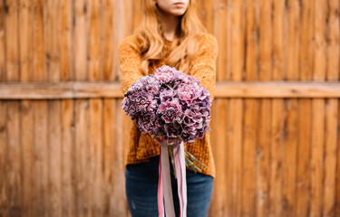 Very nice young woman holding big and beautiful bouquet of fresh flowers in colors
