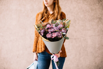 Very nice young woman holding big and beautiful mono bouquet of fresh purple carnation flowers and eucalyptus