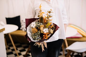 Very nice young woman holding big and beautiful bouquet of fresh flowers in colors