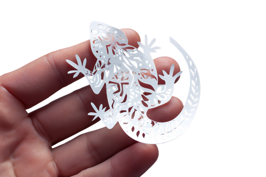 Hand holding a delicate white paper cut lizard isolated on transparent background