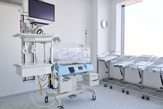 Medical equipment setup in a neonatal care unit with incubators and monitors in a bright hospital room