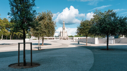Grand view of Basilica of Our Lady of the Rosary bell tower across sunny plaza with trees at...