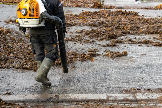 Oslo, Norway - November 28, 2025: Professional Landscaper Using Stihl Backpack Blower to Clear Wet Autumn Leaves