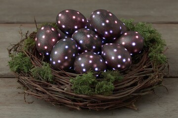 Illuminated Eggs in a Nest Cosmic Easter Decorations on Wooden Surface.