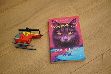 Naklejka premium A Polish edition of the book 'Warriors: Into the Wild' with a toy helicopter