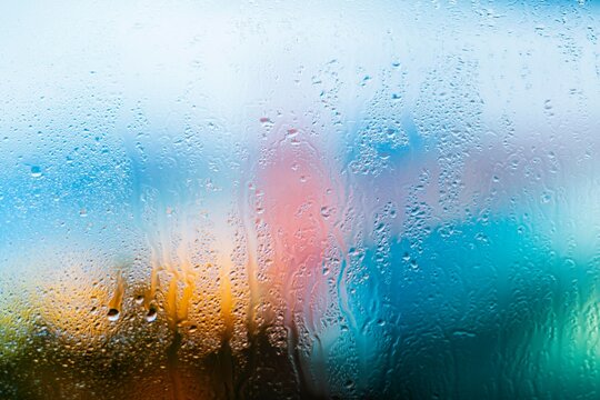 Abstract background of colorful blurred shapes and water droplets on glass creating a dreamy and atmospheric effect