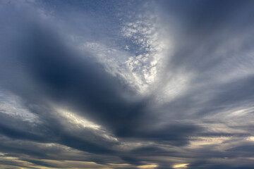 Layered grey clouds sweeping across a soft evening sky