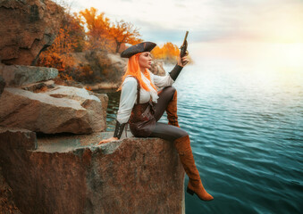 art photo real person fantasy woman pirate plans robbery armed with pistol gun holding in hands old style weapon. Sexy girl thief sitting on rocks stone beach sea blue water. brown costume high boots