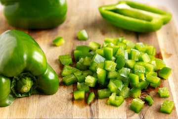 Organic Chopped Green Bell Peppers arranged on a Cutting Board, side view. Close-up.