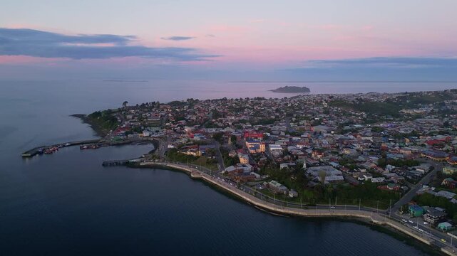 Chiloe Island, Chile: Dramatic aerial footage of sunset over Ancud in Chiloe Island in Lake District of Chile. Taken with backward motion showing the coastal road, the fisherman harbor and the city