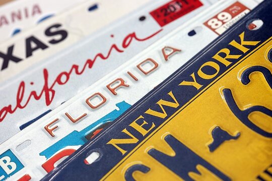 Old US car license plates with various state names close up. Concept of driving in United States. Reaching a car registration