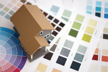 Small toy house and papers with color palette samples. Concept of interior and exterior design and painting. Color spectre for choosing tone