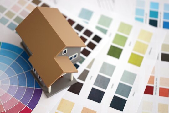 Small toy house and papers with color palette samples. Concept of interior and exterior design and painting. Color spectre for choosing tone