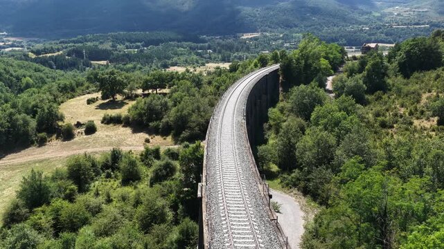 Impressive railway viaduct curves gracefully through a lush green valley, offering scenic views of the surrounding landscape