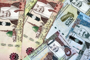 Saudi Arabia riyal money bills banknotes lies in big pile on table close up. Concept of finances and business in Saudi Arabia