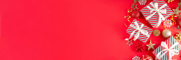 Bright red Christmas, New Year background with Christmas tree balls and decorations, holiday gift boxes, baubles, flat lay on red backdrop. Boxing day sale seasonal promotion background.
