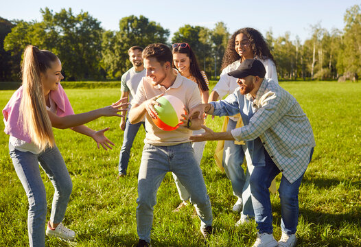 Happy diverse group of young people friends playing ball together in park, sunny outdoor, excited, celebrating achievement or victory gesture of triumph, success, unity smiling joyful positive energy
