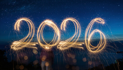 Sparkling light trails form the year 2026 against a dark blue starry night sky, symbolizing hope and anticipation for the future year ahead.