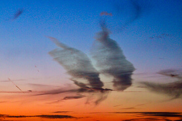 Ethereal Sunset Sky with Unique Cloud Formations. cloud shape resembling angel wings.