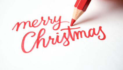 A red pencil writes merry Christmas on paper