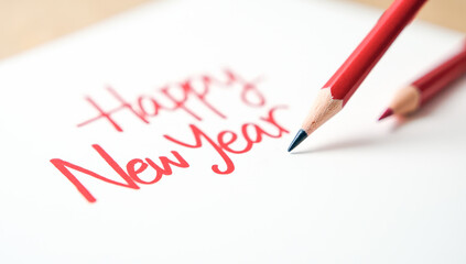 A red pencil writes happy New year on paper